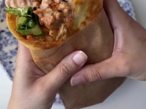 Crispy chipotle chicken wrap cut diagonally with melted cheese and creamy sauce oozing out.