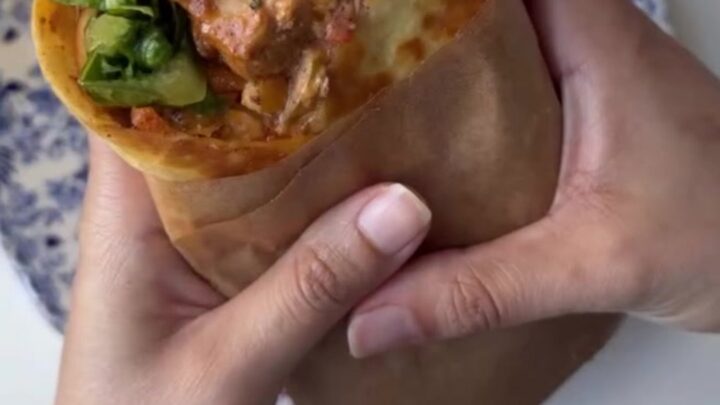 Crispy chipotle chicken wrap cut diagonally with melted cheese and creamy sauce oozing out.