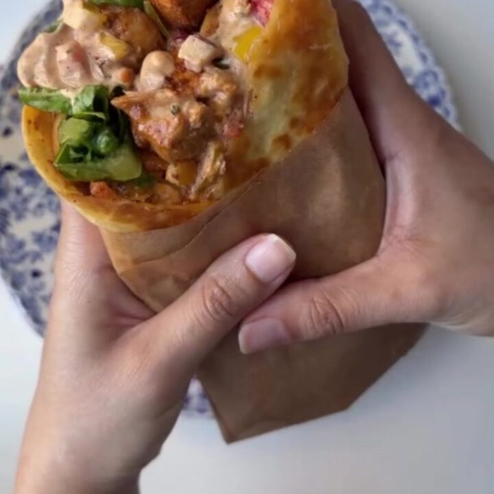 Crispy chipotle chicken wrap cut diagonally with melted cheese and creamy sauce oozing out.