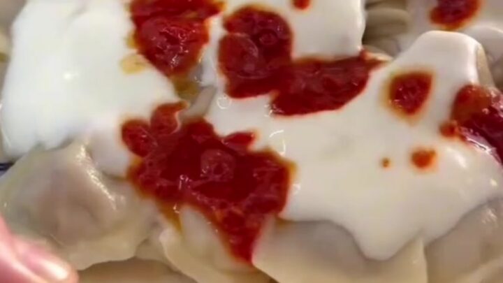 A bowl of Turkish manti dumplings topped with garlic yogurt and sizzling red paprika butter.