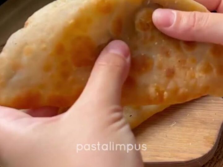 Golden puffed çi börek on a wire rack, blistered crust, steam rising, savory meat filling visible.
