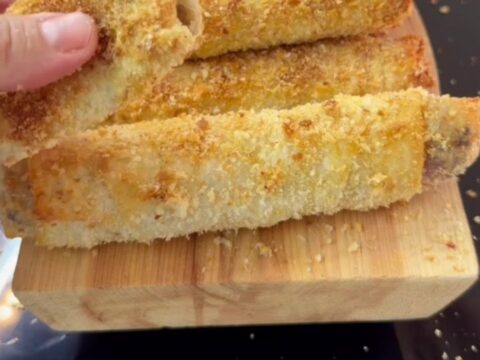 Crispy golden Paçanga böreği rolls on a plate, one torn open with melted cheese stretching