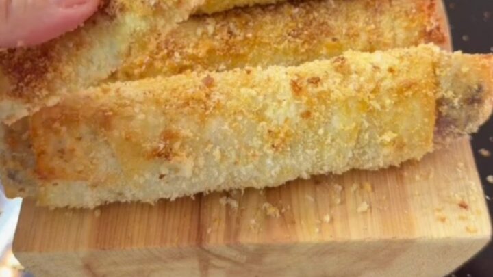 Crispy golden Paçanga böreği rolls on a plate, one torn open with melted cheese stretching