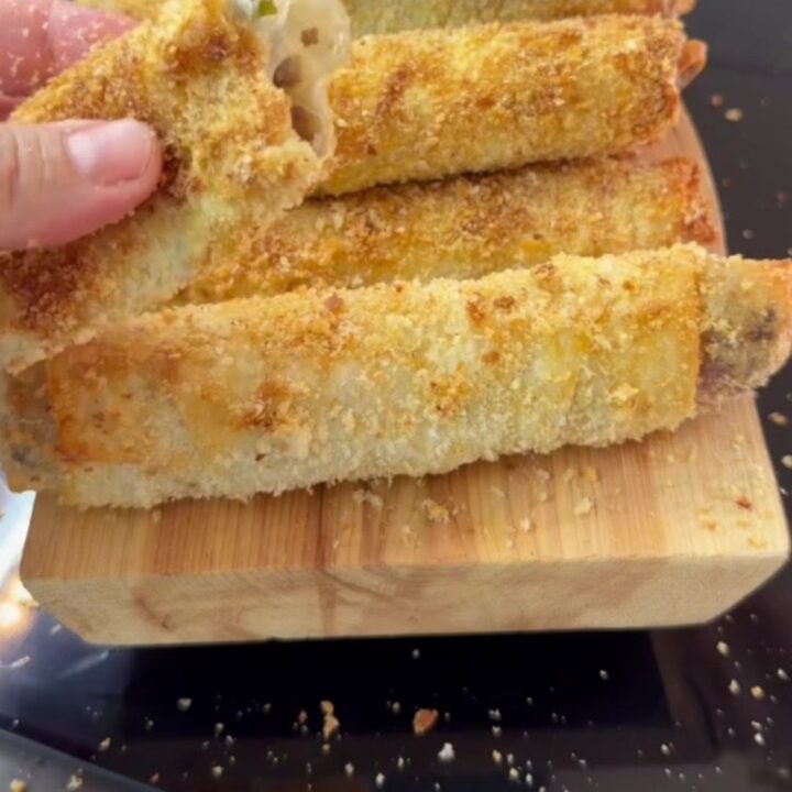 Crispy golden Paçanga böreği rolls on a plate, one torn open with melted cheese stretching