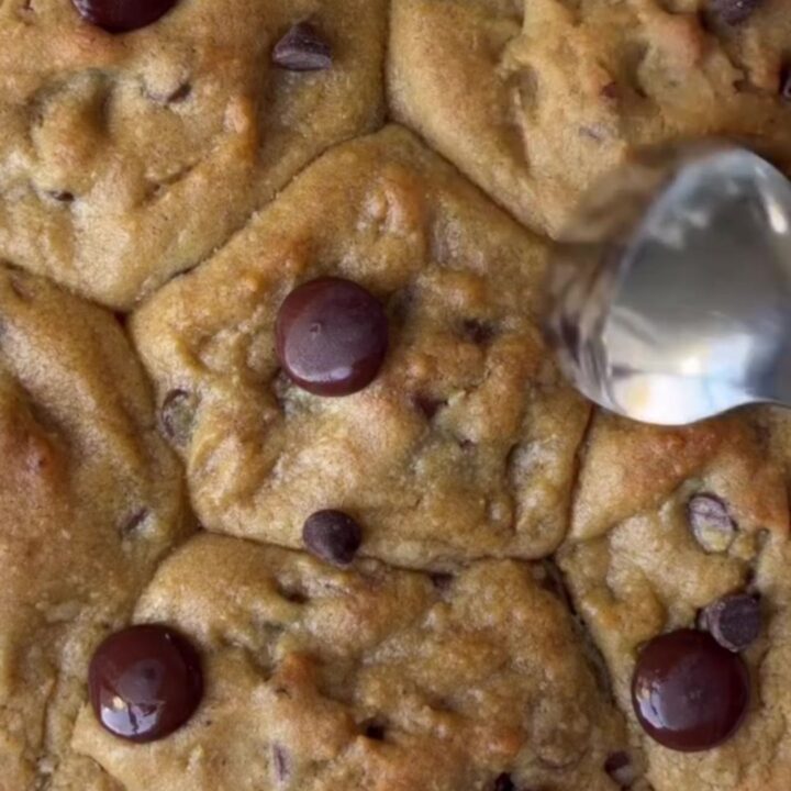 Crispy edge chocolate chip cookies with melted chocolate and flaky sea salt on a cooling rack