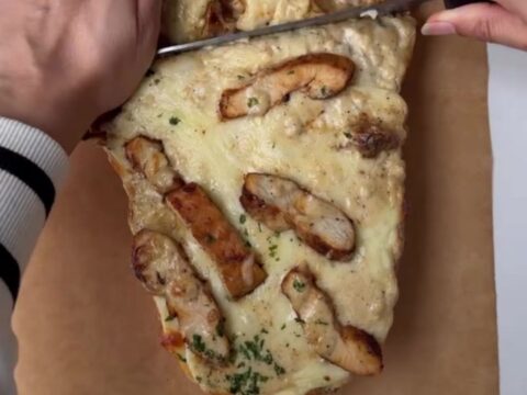 Cheesy chicken Alfredo stuffed garlic bread on a baking sheet, with melted mozzarella and golden crust.