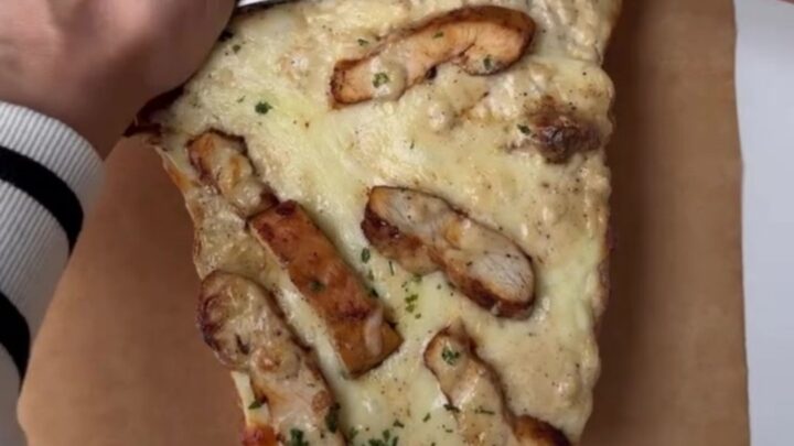 Cheesy chicken Alfredo stuffed garlic bread on a baking sheet, with melted mozzarella and golden crust.