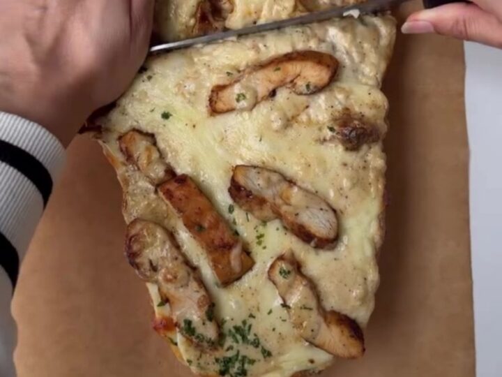 Cheesy chicken Alfredo stuffed garlic bread on a baking sheet, with melted mozzarella and golden crust.