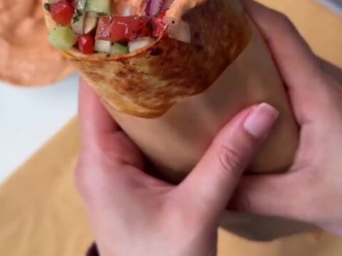Toasted chicken kebab wrap cut in half, showing juicy spiced chicken, charred peppers, and creamy garlic sauce.