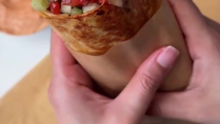 Toasted chicken kebab wrap cut in half, showing juicy spiced chicken, charred peppers, and creamy garlic sauce.
