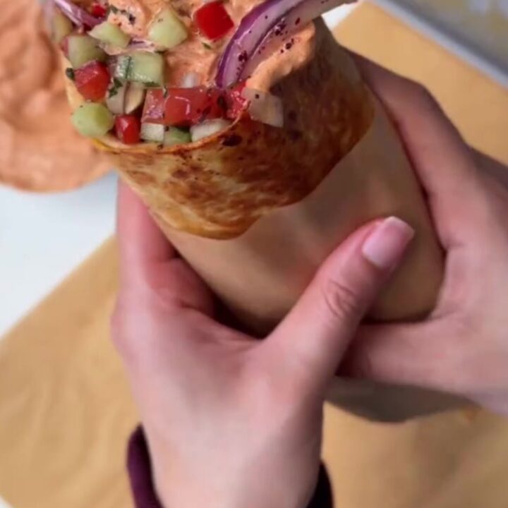 Toasted chicken kebab wrap cut in half, showing juicy spiced chicken, charred peppers, and creamy garlic sauce.