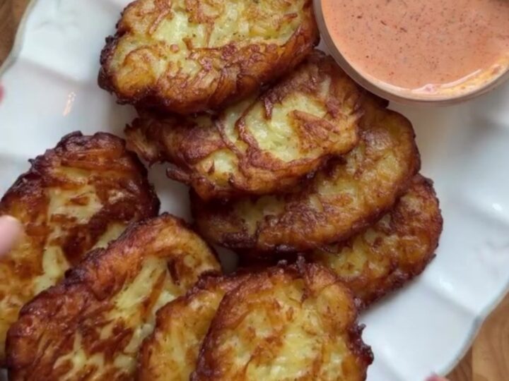 Golden crispy garlic parmesan hashbrowns stacked on a plate with a fork breaking one open