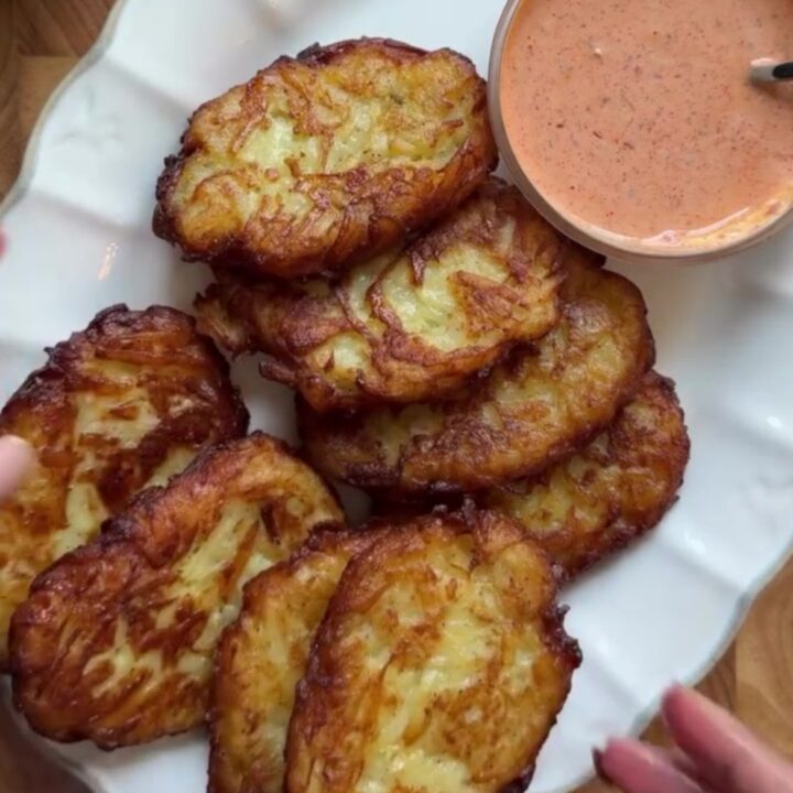 Golden crispy garlic parmesan hashbrowns stacked on a plate with a fork breaking one open