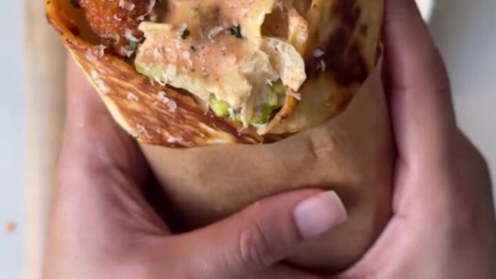 Golden toasted chicken Caesar wrap cut in half, showing crispy chicken and romaine