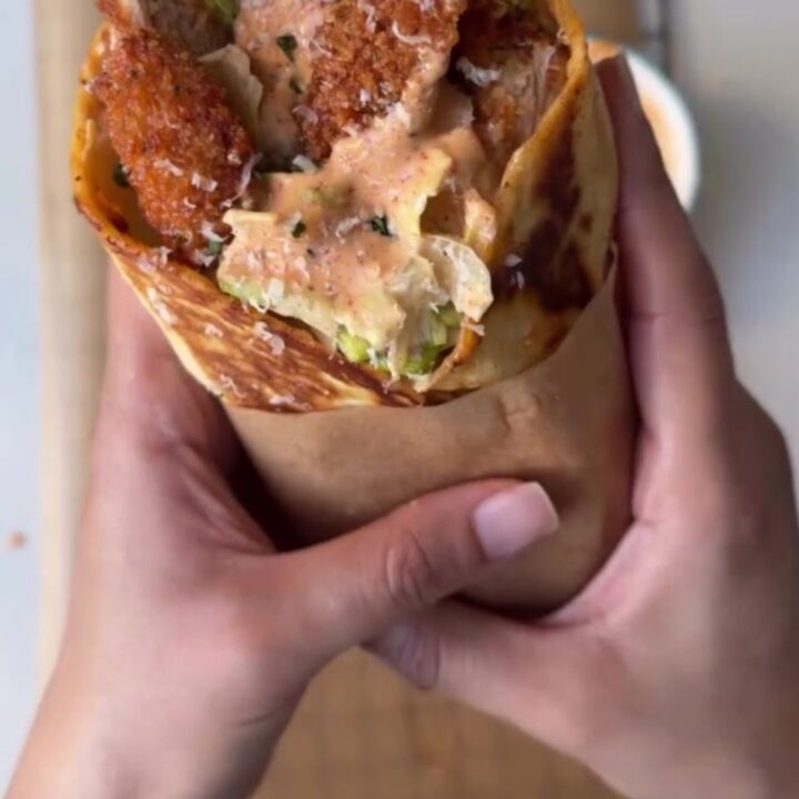 Golden toasted chicken Caesar wrap cut in half, showing crispy chicken and romaine