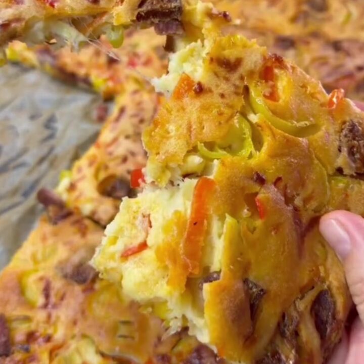 Thick sheet-pan pizza with melted mozzarella, sucuk slices, and sweet peppers on a golden crust