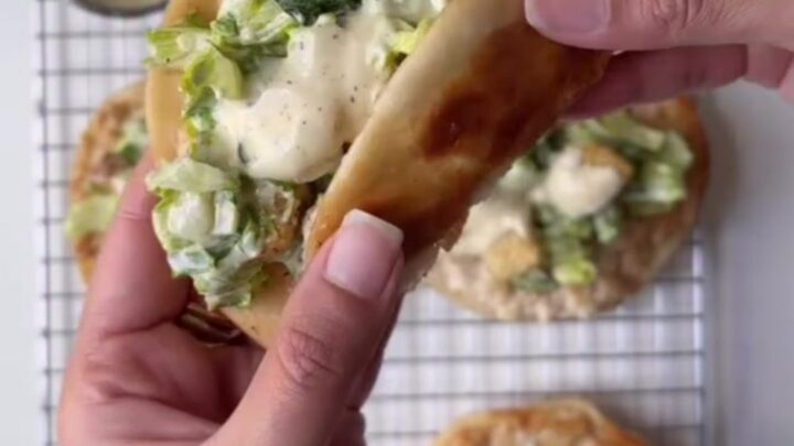 Crispy smashed chicken Caesar tacos piled high with romaine and parmesan on a platter
