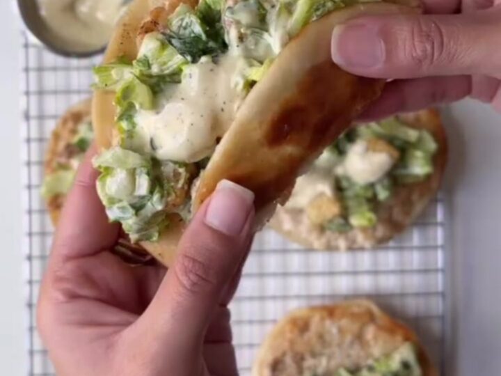 Crispy smashed chicken Caesar tacos piled high with romaine and parmesan on a platter