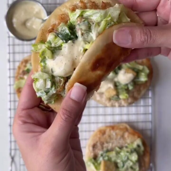 Crispy smashed chicken Caesar tacos piled high with romaine and parmesan on a platter