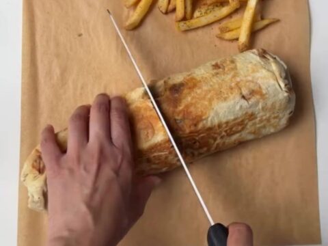 Crispy chicken lavash wrap cut in half, showing melted cheese and chicken, with garlic sauce for dipping