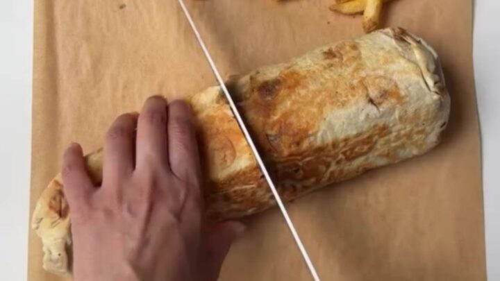 Crispy chicken lavash wrap cut in half, showing melted cheese and chicken, with garlic sauce for dipping