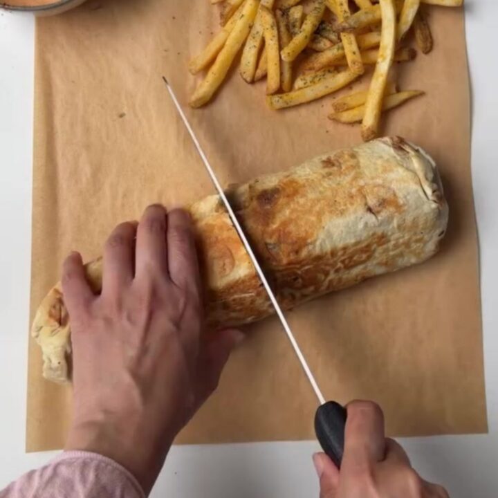 Crispy chicken lavash wrap cut in half, showing melted cheese and chicken, with garlic sauce for dipping