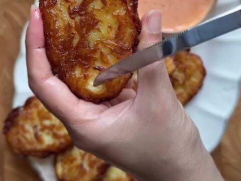Golden crispy garlic parmesan hashbrowns stacked on a plate, with a crackly crust and fluffy interior.