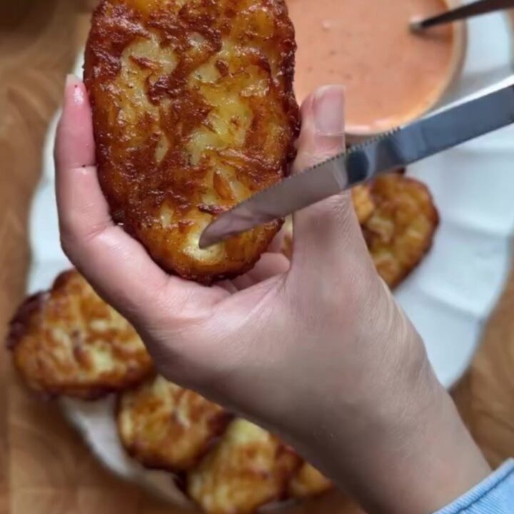 Golden crispy garlic parmesan hashbrowns stacked on a plate, with a crackly crust and fluffy interior.