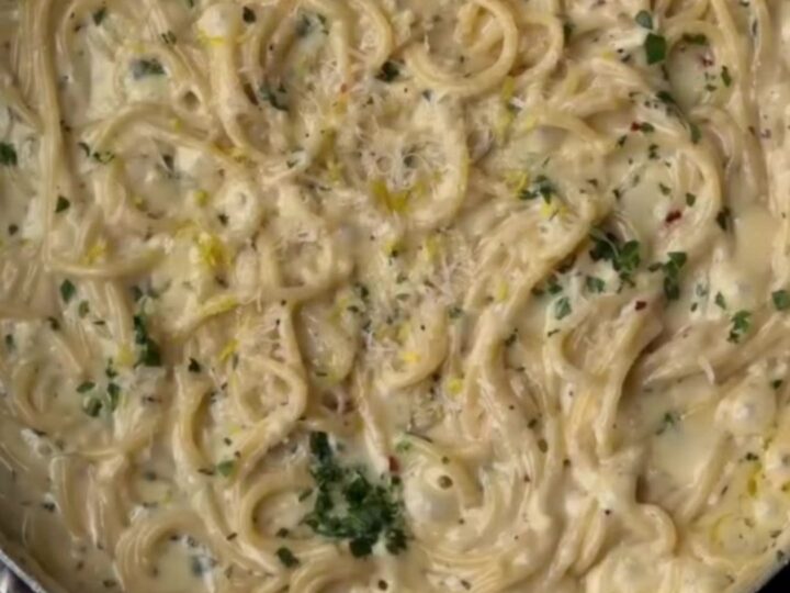 Creamy lemon garlic spaghetti twirled on a fork, coated in silky sauce with parsley and black pepper