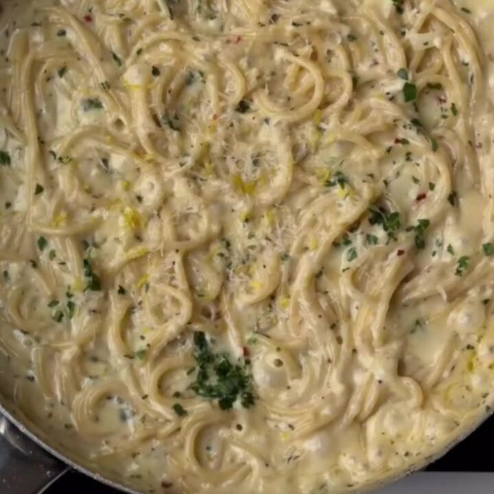 Creamy lemon garlic spaghetti twirled on a fork, coated in silky sauce with parsley and black pepper