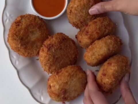 Golden fried croquettes with creamy chipotle dipping sauce on a wooden board