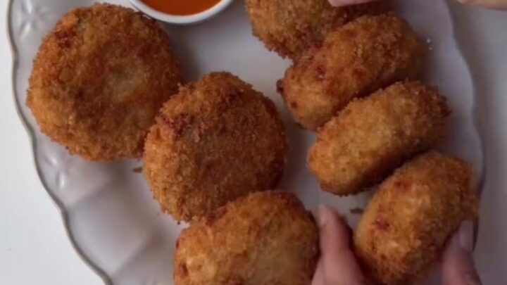 Golden fried croquettes with creamy chipotle dipping sauce on a wooden board