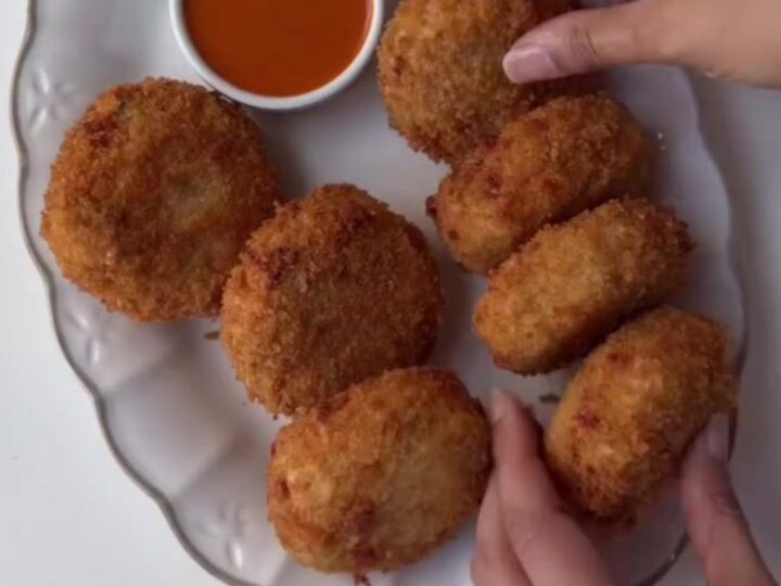 Golden fried croquettes with creamy chipotle dipping sauce on a wooden board