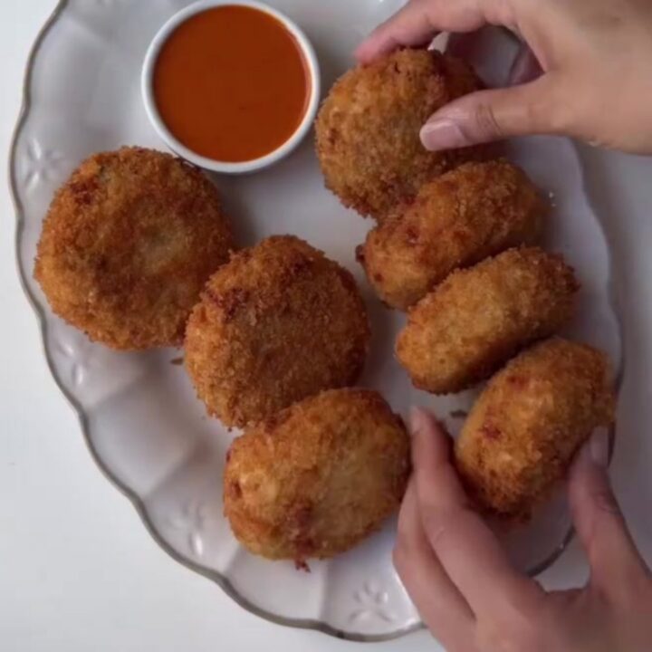 Golden fried croquettes with creamy chipotle dipping sauce on a wooden board