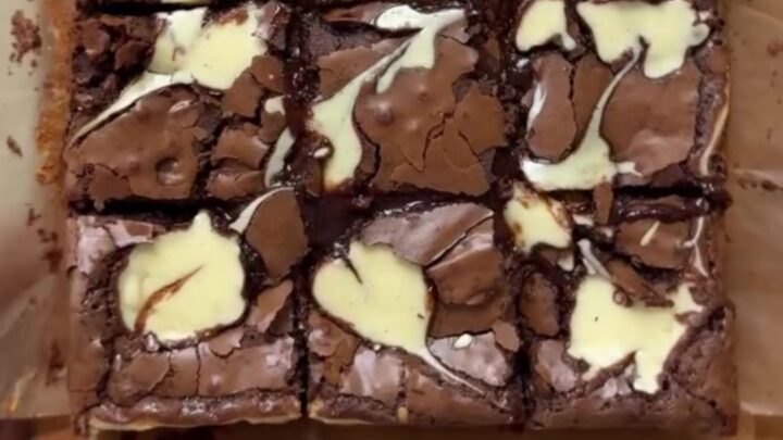 A stack of fudgy brown butter cheesecake brownies with visible swirls on a plate.