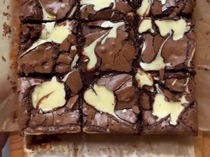 A stack of fudgy brown butter cheesecake brownies with visible swirls on a plate.