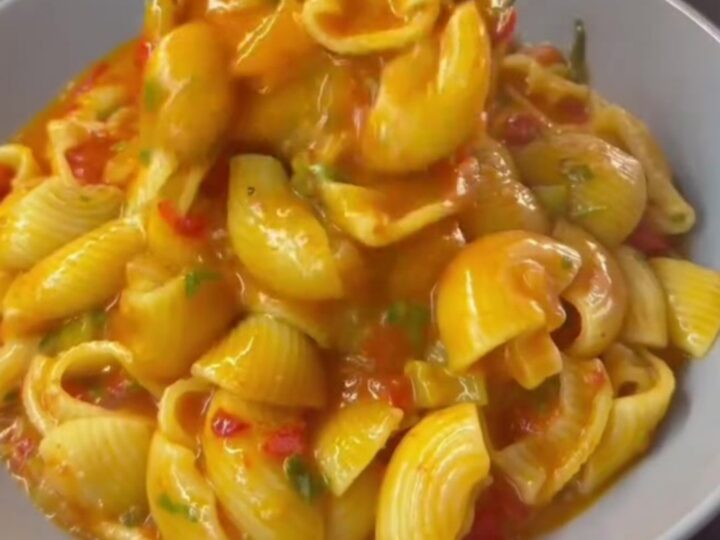 Shell pasta in a creamy roasted tomato and red pepper sauce with melted mozzarella, garnished with parsley.