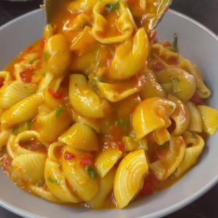 Shell pasta in a creamy roasted tomato and red pepper sauce with melted mozzarella, garnished with parsley.