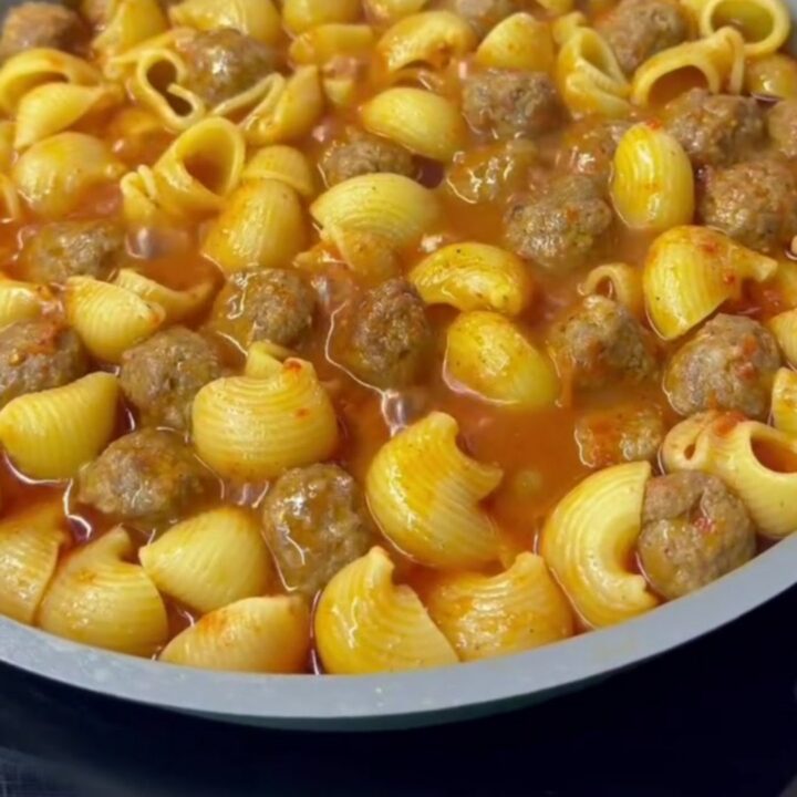 One-pot meatball pasta with penne, mini beef meatballs, and melted mozzarella in a rich tomato sauce, garnished with parsley.