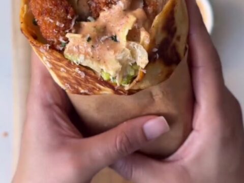 Golden toasted spicy chicken Caesar wrap cut in half, showing crispy chicken, romaine, and parmesan.