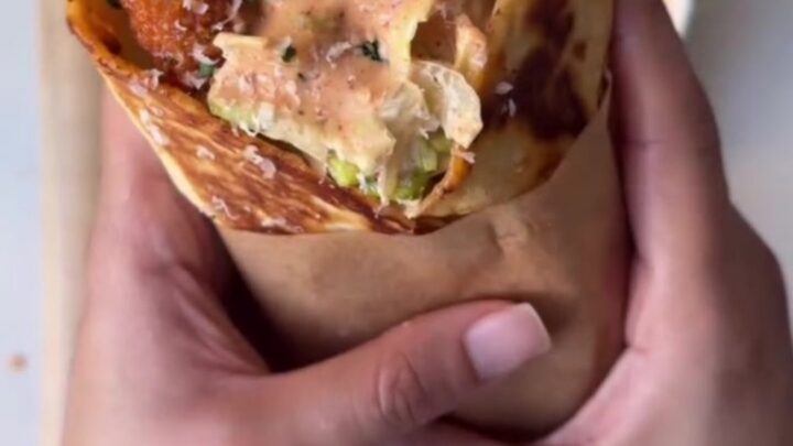 Golden toasted spicy chicken Caesar wrap cut in half, showing crispy chicken, romaine, and parmesan.