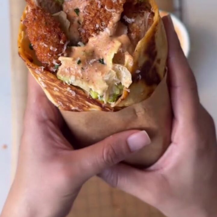 Golden toasted spicy chicken Caesar wrap cut in half, showing crispy chicken, romaine, and parmesan.