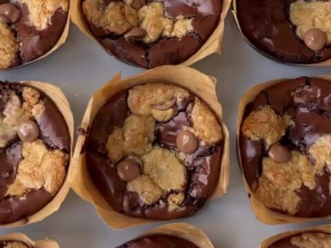 Golden brown brookie cups with flaky sea salt on a cooling rack, showing a fudgy interior