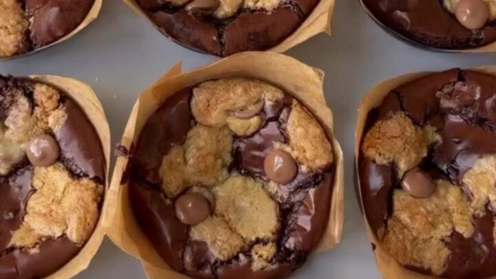 Golden brown brookie cups with flaky sea salt on a cooling rack, showing a fudgy interior