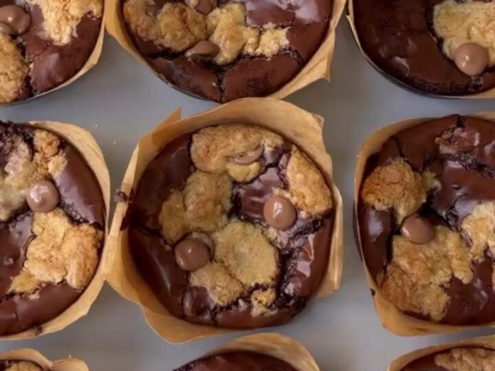 Golden brown brookie cups with flaky sea salt on a cooling rack, showing a fudgy interior