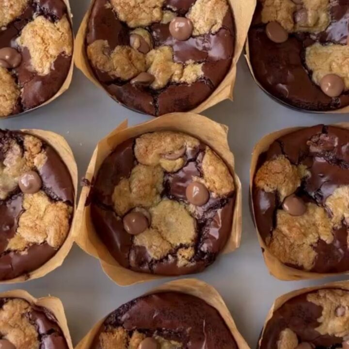 Golden brown brookie cups with flaky sea salt on a cooling rack, showing a fudgy interior