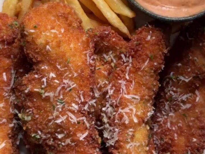 Crispy garlic parmesan chicken tenders with a creamy sweet chili dip in a small bowl, golden and crunchy.