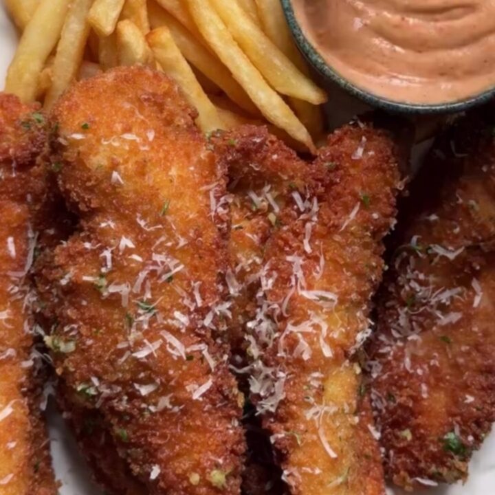 Crispy garlic parmesan chicken tenders with a creamy sweet chili dip in a small bowl, golden and crunchy.