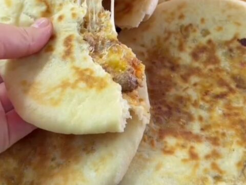 Golden pan-toasted Turkish flatbread cut in half, showing juicy spiced beef and melted cheese