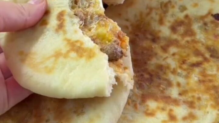 Golden pan-toasted Turkish flatbread cut in half, showing juicy spiced beef and melted cheese